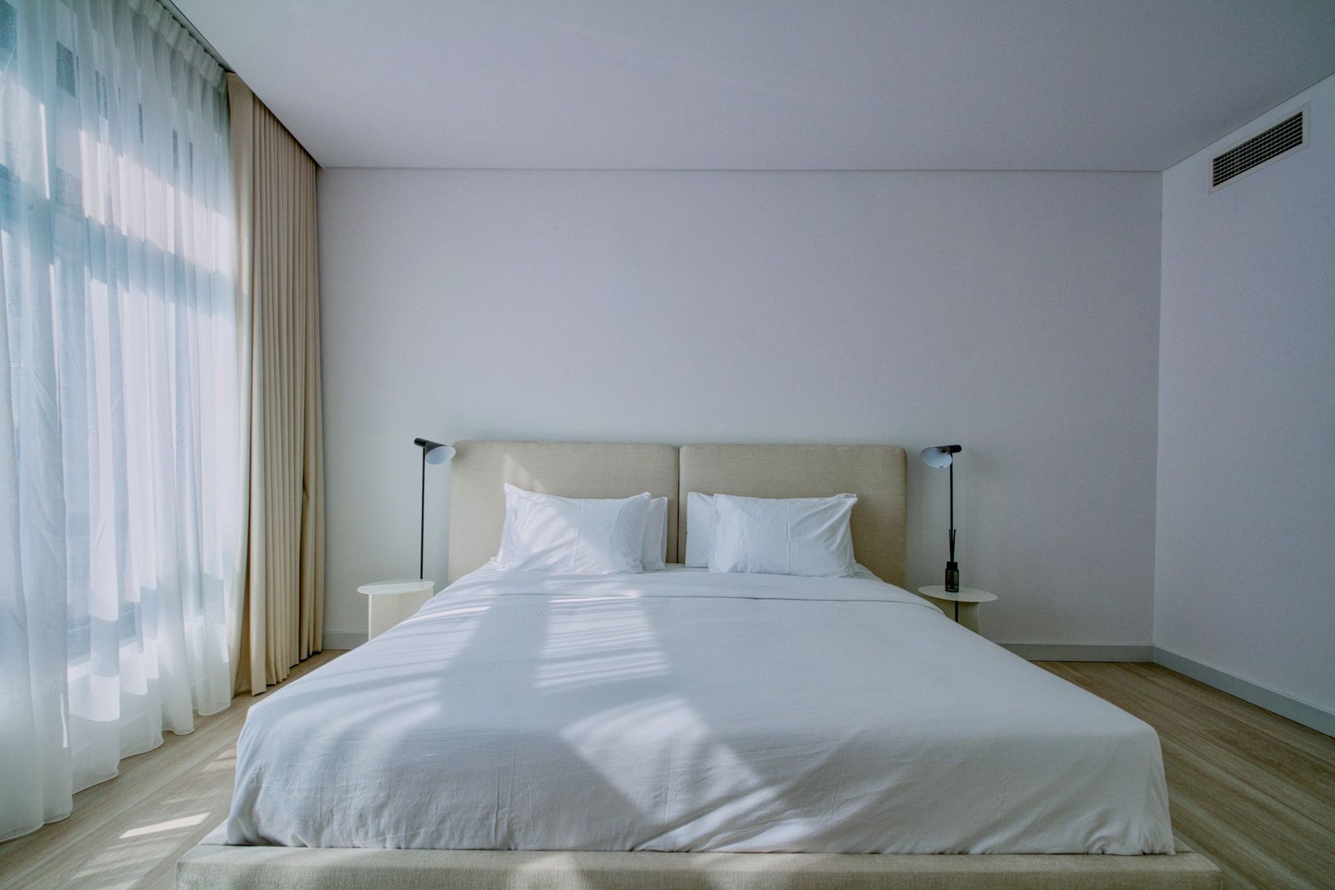 A stylish, airy bedroom interior with soft natural light and elegant furnishings.