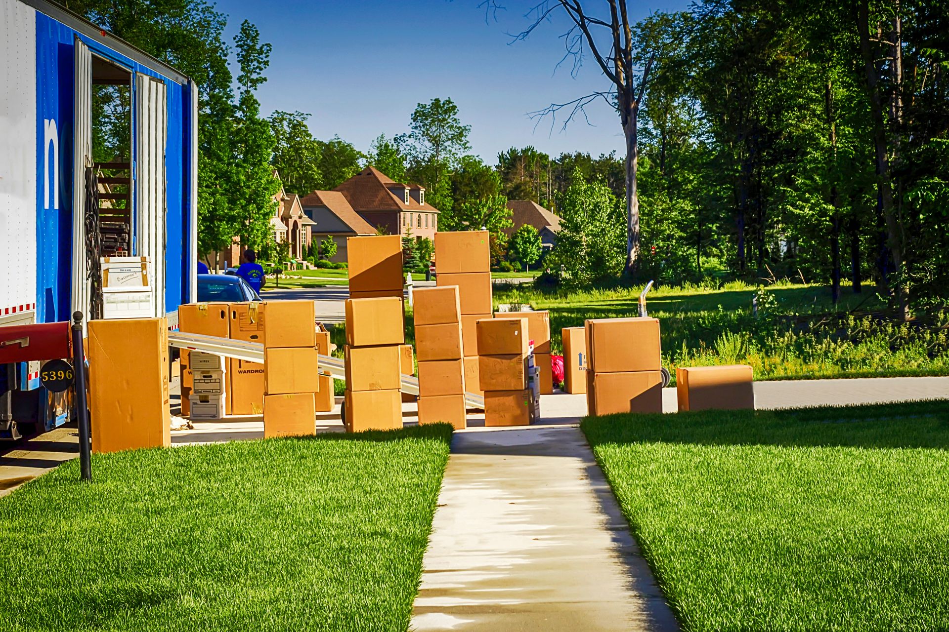 Moving truck and many cardboard boxes on a sunny lawn.